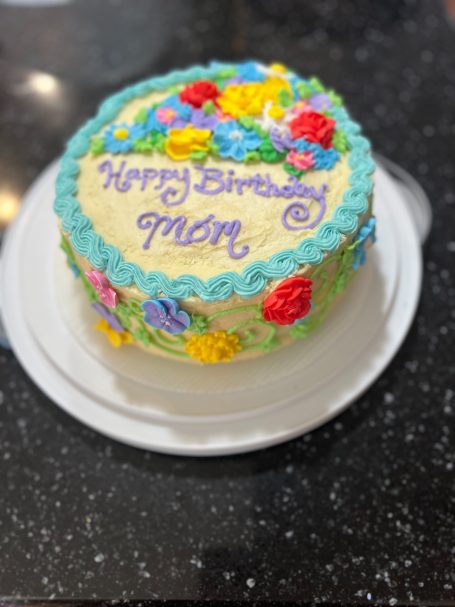 2 layer cake decorated with a vibrant flower garden, with a mix of colors that pop and many different types of flowers. 