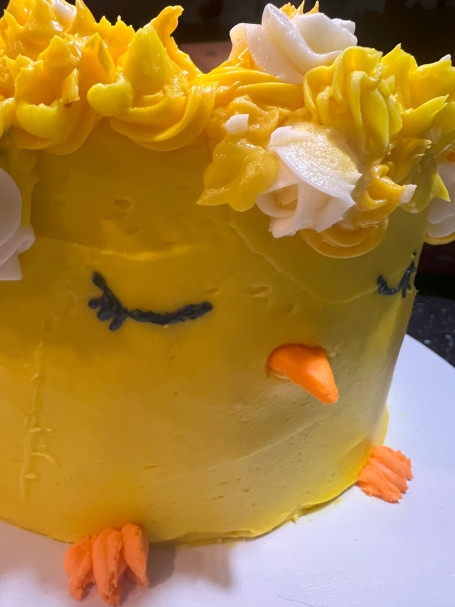 2 Layer cake elaborately decorated as a chick wearing a ring of flowers.  This is available in several flavors and sizes.